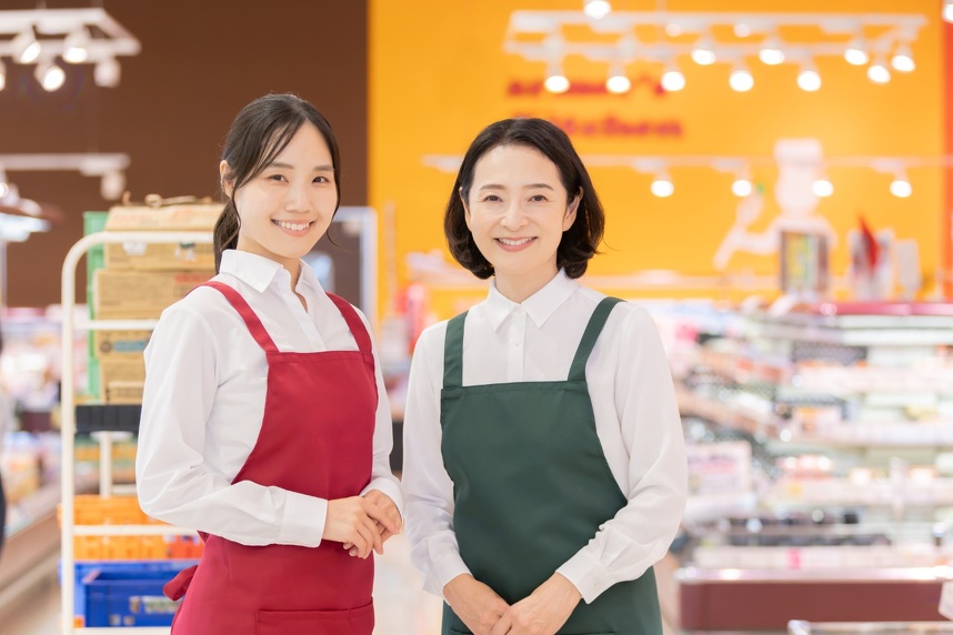 店舗にてエプロンをつけて立つ女性二人